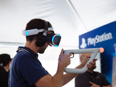 A man uses a virtual reality headset during the event.
(B Ploystation CRRRRT,man, people, woman, landscape, portrait, adult, safety, indoors, family, outdoors, business, looking, machinery, travel, drag race, wear, healthcare, young, financial security , anonymous)